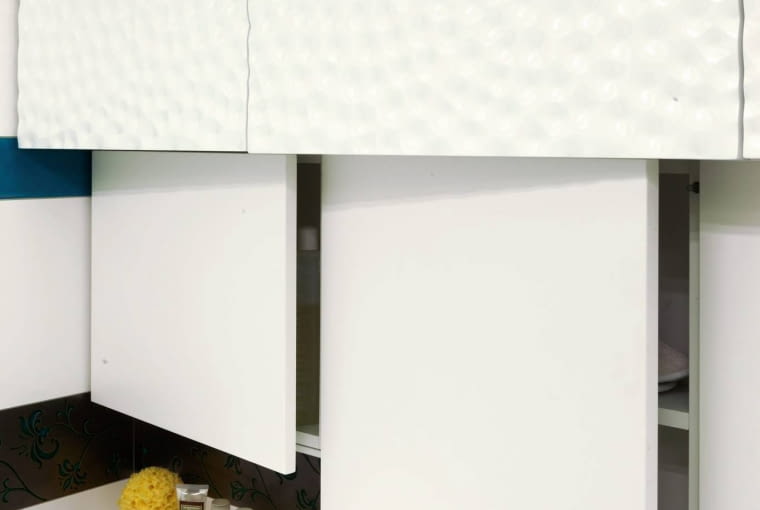 ŁAZIENKA. Szafki nie mają uchwytów. Górne schowki nad wanną są głębsze od dolnych - w jednej z nich ukryto kocioł gazowy. Przy wannie powstała mała wnęka na kosmetyki.