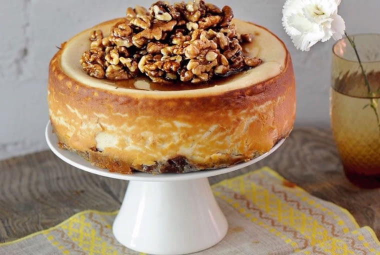 Sernik z koziego sera z miodem i orzechami Składniki: spód - 200 g ciasteczek digestive, 100 g masła; masa - 800 g koziego serka, 150 g cukru, 3 łyżki mąki pszennej, 2 jajka, szczypta soli, starta skórka z 1 pomarańczy, 1,5 łyżeczki soku z cytryny, 100 ml kwaśnej śmietany, 0,5 łyżeczki cynamonu; wierzch - 5-6 łyżek miodu, 200 g orzechów włoskich. Wykonanie: Rozgrzać piekarnik do 200sC. Pokruszyć ciasteczka i wymieszać z rozpuszczonym masłem, przełożyć na blaszkę. Ubić ser mikserem, dodać mąkę, śmietanę i cynamon, ubite na parze jajka z cukrem, skórkę pomarańczową i sok z cytryny. Masę wylać na podpieczony spód i wstawić do piekarnika. Po 10 minutach zmniejszyć temperaturę do 90sC i piec 25 min. Wyłączyć piekarnik i zostawić sernik na 2 godziny. Na patelni rozgrzać miód. Gdy zacznie się pienić, dodać orzechy i podsmażyć. Wylać na wierzch sernika i zostawić do ostygnięcia.