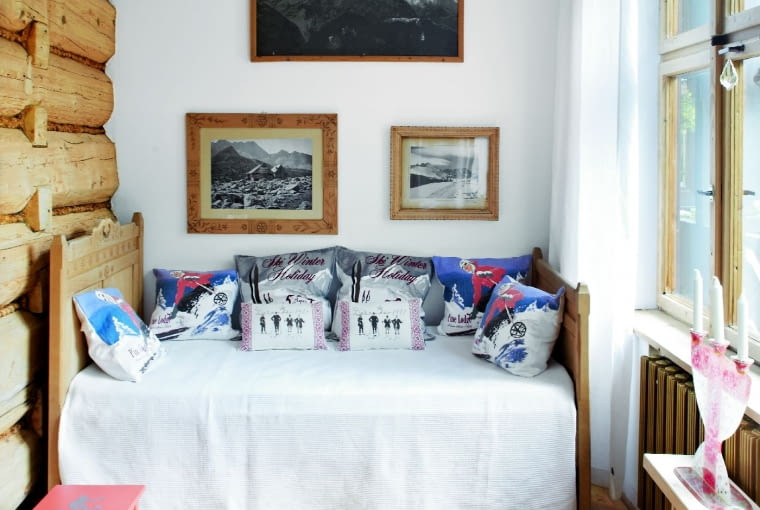 GOŚCIE nocują zwykle na... szlabanie, czyli zabytkowej wiejskiej kanapie-ławie. Poduszki z górskimi motywami przyjechały ze sklepu Alens w Sztokholmie. Na ścianie - czarno-białe fotografie Tatr.