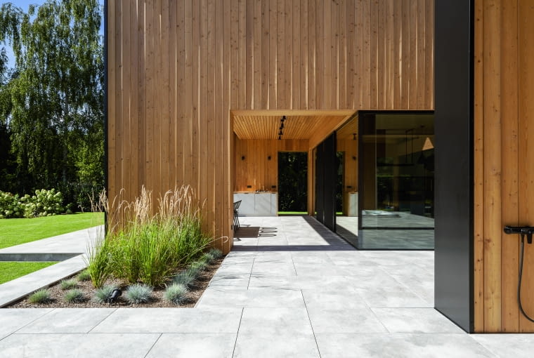 Widok „w poprzek”, z jednego tarasu na drugi. Posadzkę obu stanowią płytki gresowe, położone w technologii tarasu wentylowanego Widok „w poprzek”, z jednego tarasu na drugi. Posadzkę obu stanowią płytki gresowe, położone w technologii tarasu wentylowanego