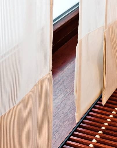 DEKORACJE - OKNA DYSKRETNIE PRZESŁONIĘTE. Zasłona panelowa ma u dołu wszyty obciążnik, dzięki czemu nie marszczy się ani nie faluje. Ekrany (tak też nazywa się panele) uszyto z tkaniny jednobarwnej oraz w paski.