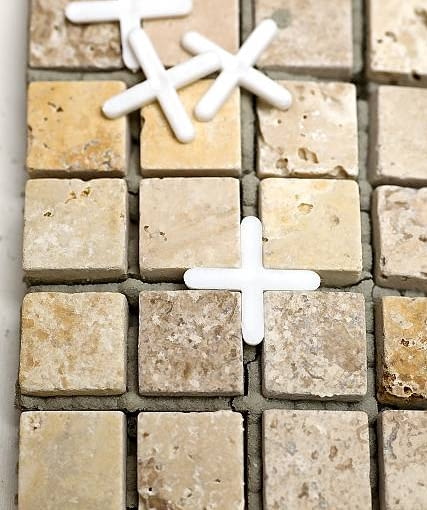 3. Aby zachować równe odstępy między kostkami mozaiki, wkładamy krzyżyki dystansujące odpowiedniej szerokości. To szczególnie ważne w miejscu łączenia dwóch płatów mozaiki. 3. Aby zachować równe odstępy między kostkami mozaiki, wkładamy krzyżyki dystansujące odpowiedniej szerokości. To szczególnie ważne w miejscu łączenia dwóch płatów mozaiki.