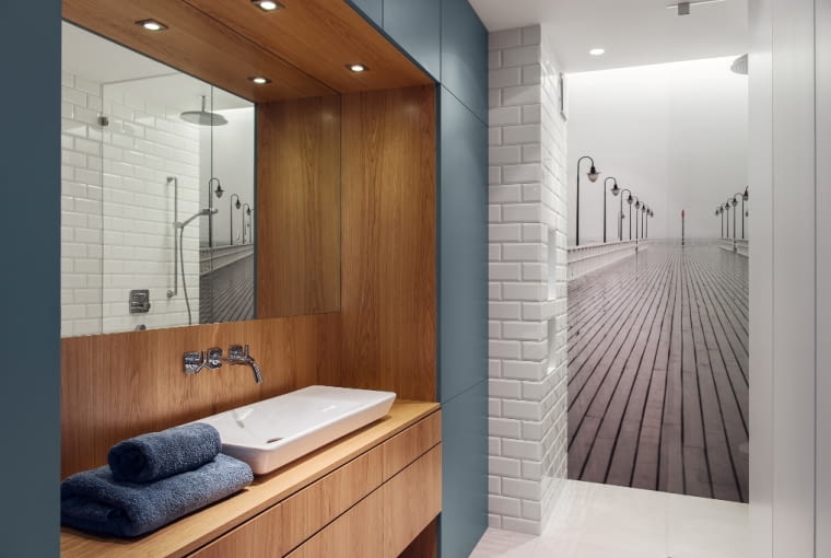 W łazience uwagę przykuwa czarno-białe zdjęcie orłowskiego molo, a także wnęka w wykończeniu z dębowej czeczoty, która pięknie kontrastuje z morską barwą meblowej zabudowy. To w niej chowają się kosmetyki, pralka, deska do prasowania i pozostałe przybory potrzebne do utrzymania porządku. Dzięki temu łazienka jest uporządkowana.