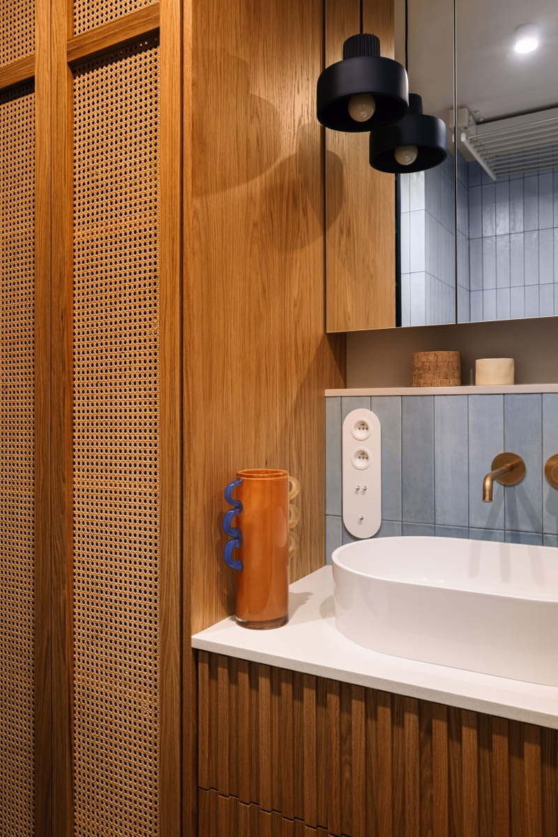 Obok znalazła się fornirowana szafa z dekoracyjną plecionką, mieszcząca pralkę i suszarkę, a całość uzupełnia dopasowana szafka umywalkowa.