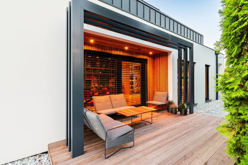 Ten sam fragment  pokazany od tyłu, czyli  od ogrodu, w kierunku  przestrzeni przed domem,  znajdującej się przy drodze  wjazdowej.  U góry widoczne ścianki  kolankowe  dwukondygnacyjnej bryły –  białe mury stanowią z kolei  fragment otaczającej ją  części parterowej, która  od tej strony poszerza  o blisko metr dostępną  przestrzeń salonu i kuchni