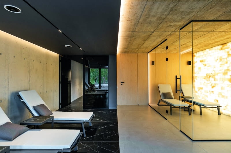 Mieć w domu saunę i jacuzzi to jedno, ale przygotować dla tych atrakcji specjalną, obszerną  przestrzeń, a w zasadzie całą kondygnację, wzbogaconą o wygodne łóżka-leżaki, głośniki  w suficie, a przede wszystkim o grotę solną – z rozjarzonych, bo podświetlanych cegieł  solnych – to już zupełnie inna skala myślenia o domowej strefie wellness-spa