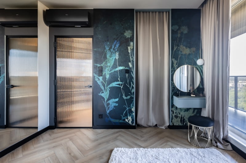 Sypialnia pełni więcej niż jedną funkcję. Oprócz nocnego wypoczynku, można tu leżąc na łóżku oglądać telewizor ustawiony na środku pomieszczenia, a także poczytać książkę w bujanym, różowym fotelu, a pani domu może poświęcić chwilę swojej urodzie przy specjalnie do tego zaplanowanym miejscu z toaletką. Bezpośrednio z sypialni prowadzi wejście do wspomnianej, osobistej, niedostępnej dla gości łazienki oraz do garderoby za beżową zasłonką.