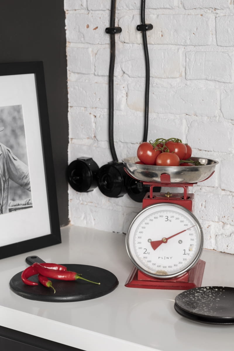 Czerwień, podobnie jak czerń i granat użyte w projekcie wnętrza, wzbogacają aranżację. Czerwona, metalowa waga kuchenna, młynek do pieprzu, ekspres do kawy czy skrzynka na listy kupiona przez Tomka w miejscowym sklepie z różnościami, idealnie wpisują się w industrialne tło mieszkania. Ciemne, ceramiczne talerze kupiono w sklepie Dutchhouse.