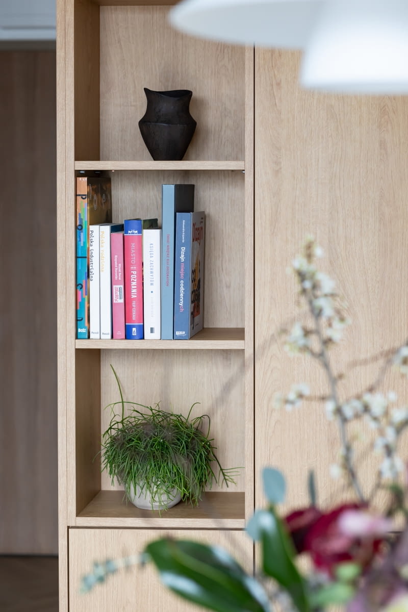 Do zabudowy kubika wykorzystano płytę laminowaną Dąb Corbridge naturalny z oferty marki Egger. Nowoczesną bryłę urozmaica wnęka z kilkoma półkami na książki i dekoracje. Całość wykonała poznańska firma stolarska – Płuciennik.