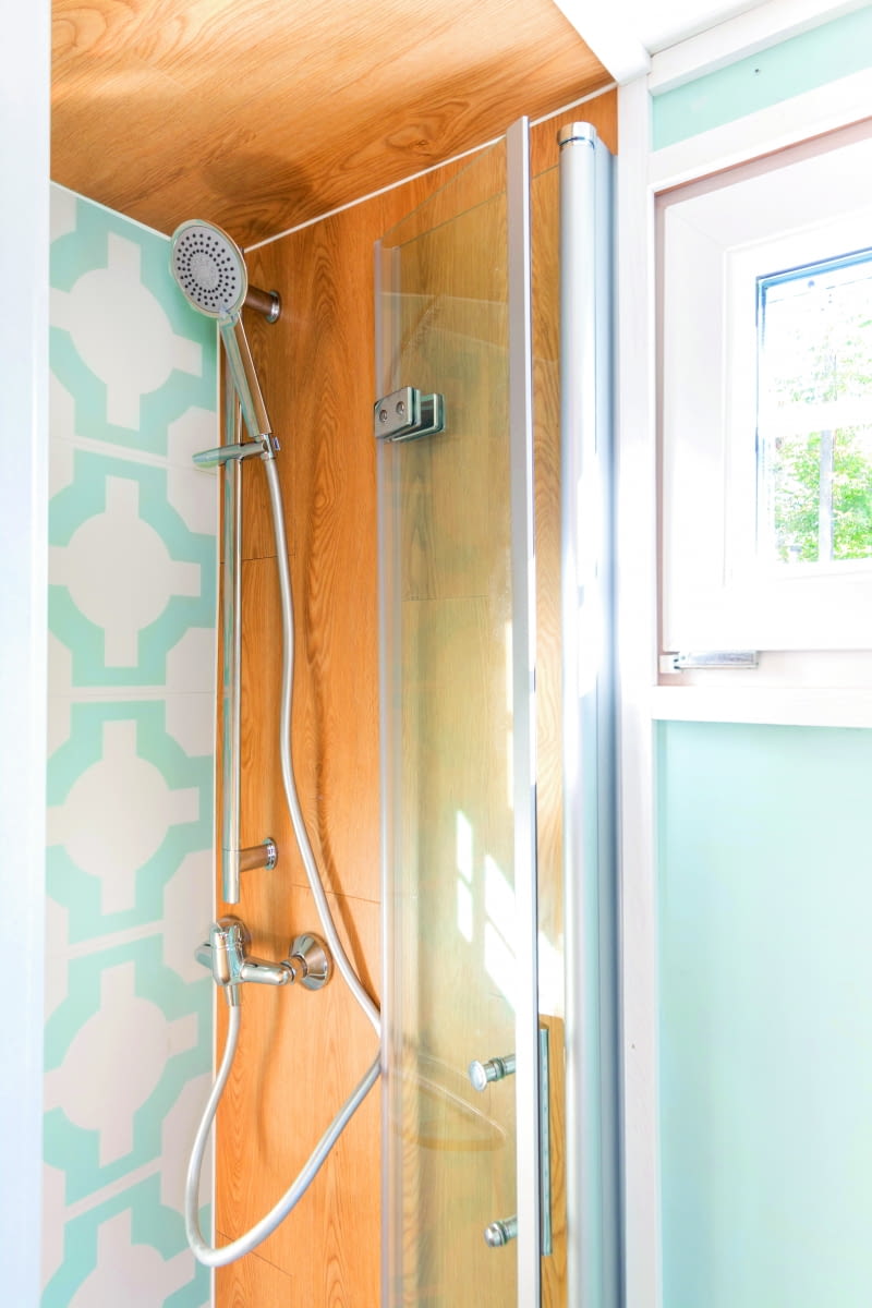 W łazience projektantka zaplanowała prysznic, zamykany składanymi drzwiami. Do wykończenia ściany użyto tych samych płytek winylowych, które zdobią podłogę domu