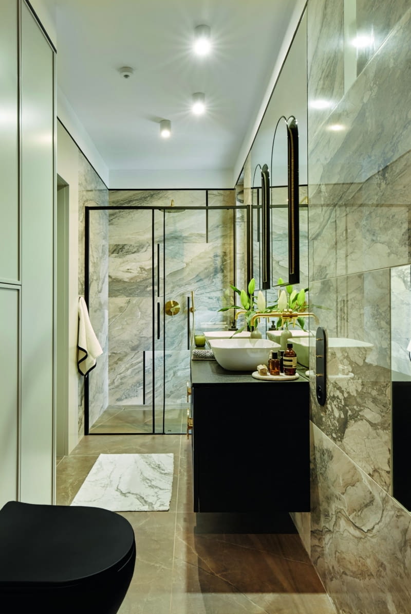 Płytki ścienne oraz podłogowe w kolorach ziemi urozmaicają, podobnie jak w łazience synów, czarne elementy. Linię zasięgu płytek pod sufitem wyznacza metalowa, czarna listewka zlicowana z gresem i powierzchnią ściany. Zabieg ten dodaje elegancji i podkreśla kompozycyjną całość elementów zastosowanych w pomieszczeniu.