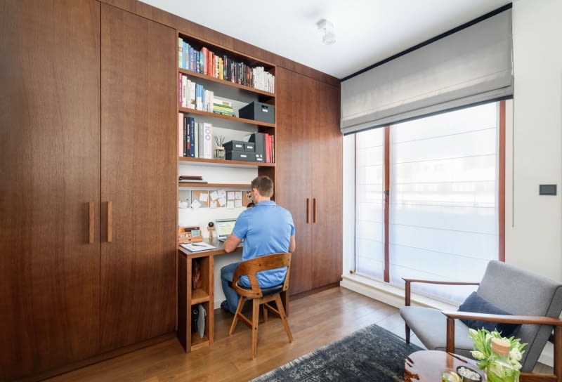 W gabinecie do pracy, z którego korzysta Michał, wygospodarowano szafy pełniące funkcję garderoby. Aby nie zdominowały swoją funkcją pomieszczenia, w którym odbywają się służbowe spotkania męża, Marta urozmaiciła ich wygląd. Te wykończone ciemnym fornirem rozdziela, nadająca lekkości całościennej zabudowie, wnęka z biurkiem i półkami. Szafa po drugiej stronie pokoju zaskakuje przyjemnym dla oka i w dotyku wykończeniem przesuwnych drzwi, na które wybrano tapetę ze sklepu ABC Tapety.