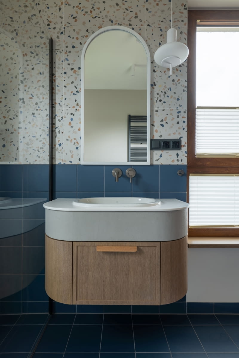 W łazience dzieci uwagę przyciąga też szafka umywalkowa wykonana na zamówienie – z blatem z konglomeratu, betonową opaską i fornirowanym dołem. Piękne, białe wiszące lampy wyprodukował Ummo Lighting.