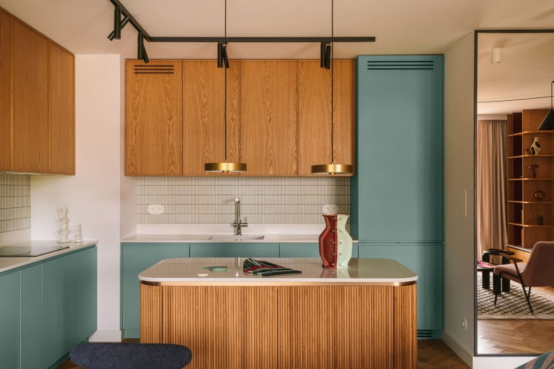 Zieleń lakierowanych frontów kuchennych zestawiono z naturalnym fornirem dębowym. Zielone są również fugi, których użyto przy układaniu białej mozaiki marki Dunin, chroniącej ściany nad blatami.