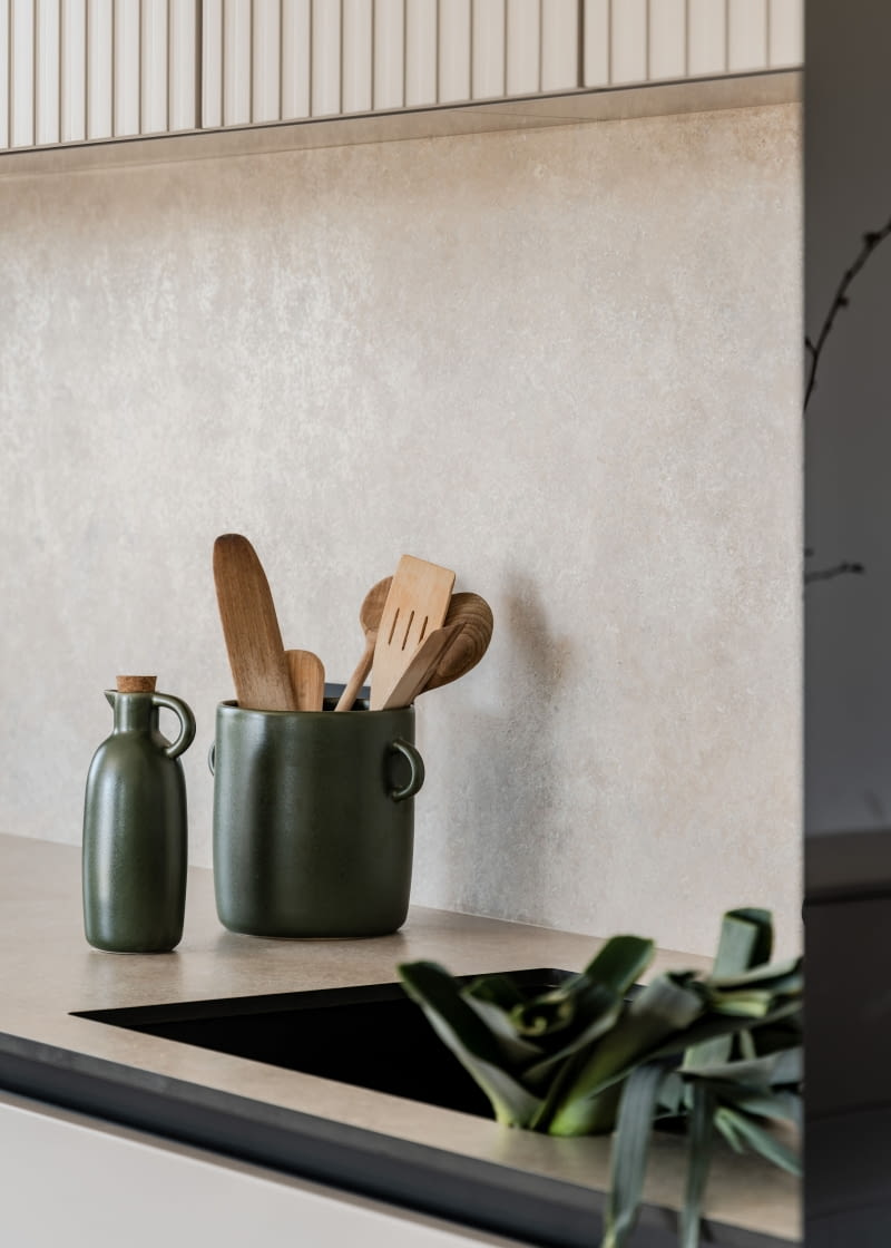 Na blat kuchenny i ściankę powyżej wybrano płytę kompaktową Egger Tessina Ceramic kremową F221ST87 – z delikatną perłowo-satynową poświatą.