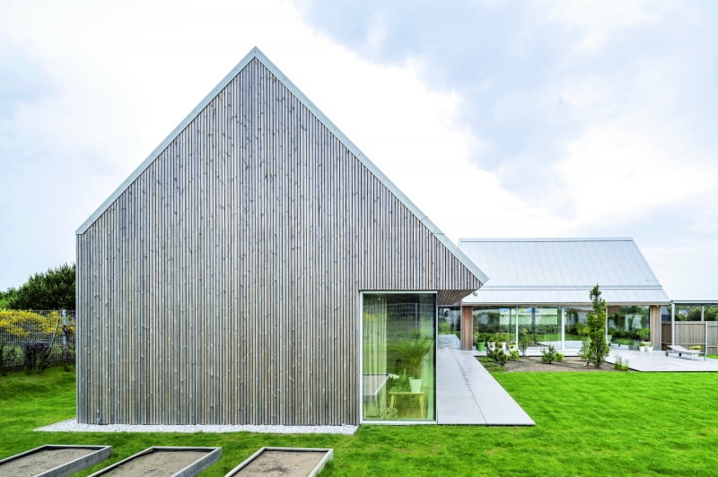 Dwuspadowy dach pokryto jasnoszarą blachą na rąbek, nawiązującą kolorystycznie do palety pozostałych materiałów użytych w projekcie, stonowanych i naturalnych, takich jak beton, granit, gres czy jesion