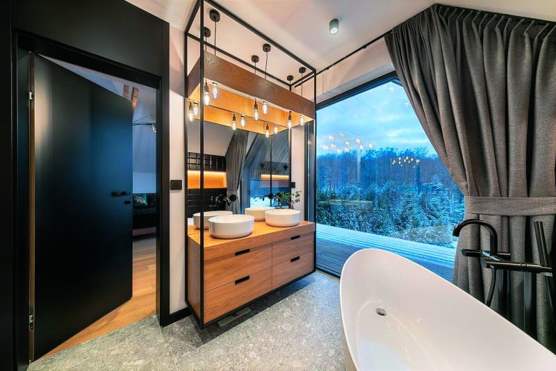 Łazienka właścicieli, przylegająca do ich sypialni – tej z żyrandolem jak rondo letniego kapelusza i botanicznym panelem. Tu panują zdecydowanie dorosłe klimaty, z obszernie aplikowaną czernią i wyrazistymi kontrastami kolorów oraz kształtów