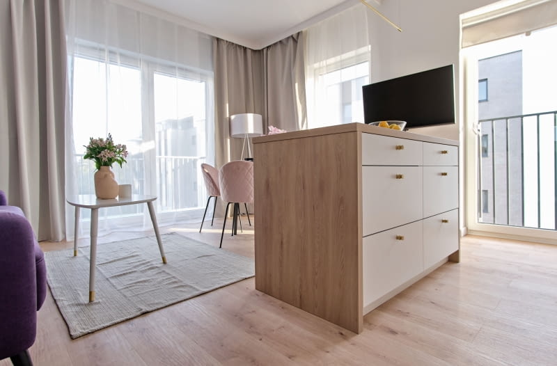 PODZIAŁ FUNKCJONALNY. Salon jest miejscem, w którym wypoczywamy, przygotowujemy posiłki, przyjmujemy rodzinę i przyjaciół. I tak jest również u Dominiki. Dodatkowo nasza projektantka postanowiła wyburzyć niewielką ściankę działową, która stała tu wcześniej. Taki zabieg pozwolił powiększyć dostępną przestrzeń tego otwartego salonu, poza tym Agnieszce zależało na swobodnym przejściu dookoła wyspy.