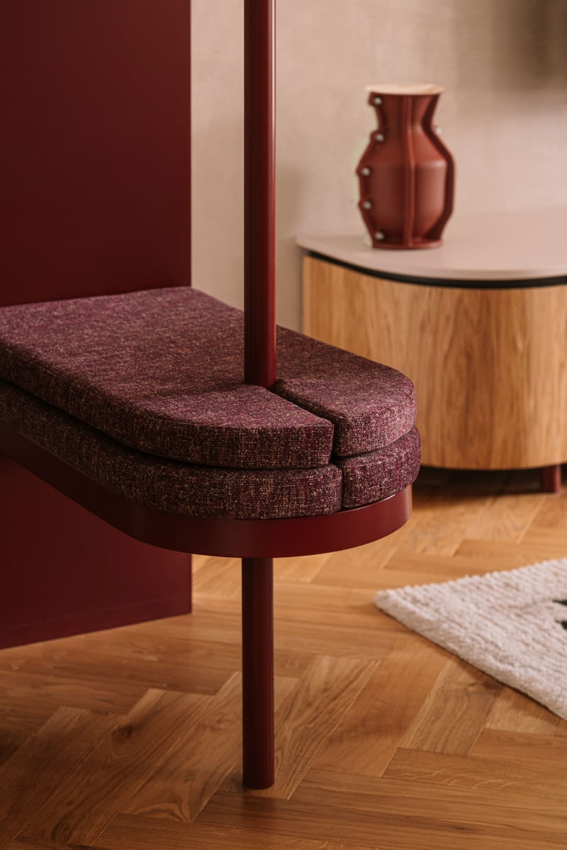 Jednym z najbardziej charakterystycznych elementów realizacji jest strefa wejściowa  z bordową ławeczką łączącą się z zabudową meblową korytarza. Wyrazisty akcent już  od progu mieszkania wprowadza do wnętrza kolor i miękką linię.