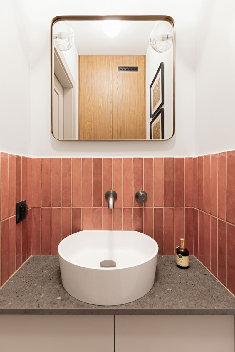 W małej toalecie zabudowę wokół podtynkowego stelaża WC wykonano z tych samych płyt co w łazience i kuchni — to przewodni kolor mieszkania. Kryje ona przyłącza i liczniki przeniesione tu po remoncie sąsiadującej łazienki. Różowe, wpadające w rudości płytki przy umywalce współgrają z blatem ze spieku kwarcowego, wykorzystanego również w kuchni. W małej toalecie zabudowę wokół podtynkowego stelaża WC wykonano z tych samych płyt co w łazience i kuchni — to przewodni kolor mieszkania. Kryje ona przyłącza i liczniki przeniesione tu po remoncie sąsiadującej łazienki. Różowe, wpadające w rudości płytki przy umywalce współgrają z blatem ze spieku kwarcowego, wykorzystanego również w kuchni.