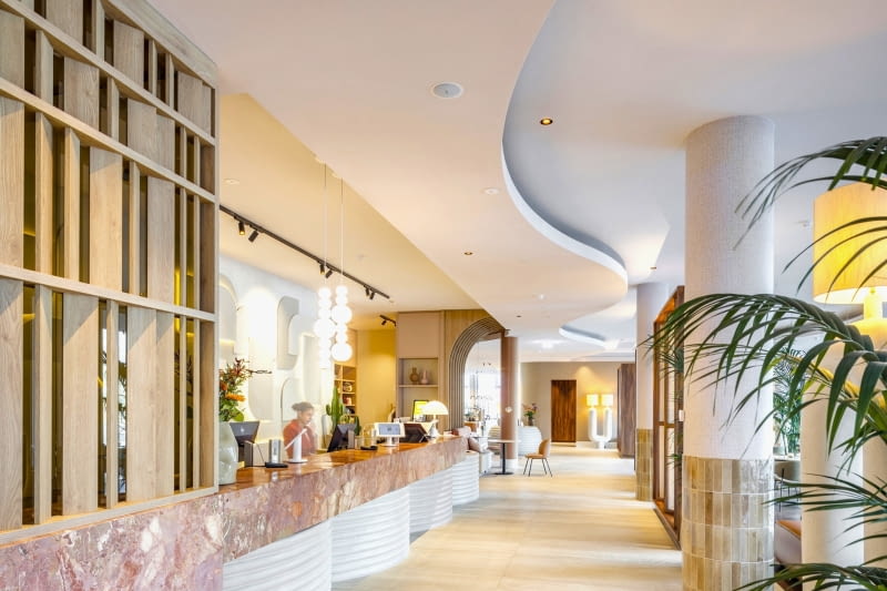 Falujące kształty akustycznych sufitów Eleganza marki Knauf Ceiling Solutions współgrają z kształtami recepcji. Falujące kształty akustycznych sufitów Eleganza marki Knauf Ceiling Solutions współgrają z kształtami recepcji.