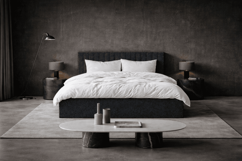 Miłe w dotyku tkaniny – tapicerka łóżka, dywan i zasłony sprawiają, że pomimo ciemnych barw sypialnia wydaje się przytulna, idealna do wyciszenia się przed snem. Miłe w dotyku tkaniny – tapicerka łóżka, dywan i zasłony sprawiają, że pomimo ciemnych barw sypialnia wydaje się przytulna, idealna do wyciszenia się przed snem.