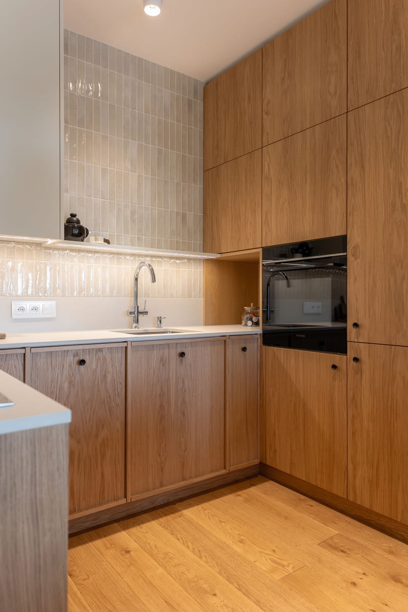 Kuchnia - górne szafki poprowadzono tylko do pewnego momentu, pozostawiając przerwę przed wysoką zabudową. Całą ścianę, wraz z tym „oddechem”  w kompozycji zdobią ręcznie formowane płytki-cegiełki marki Rondine z subtelnymi niedoskonałościami. Ciekawym rozwiązaniem jest bateria Grohe Blue Home, która umożliwia uzyskanie schłodzonej, gazowanej i filtrowanej wody bezpośrednio z kranu.