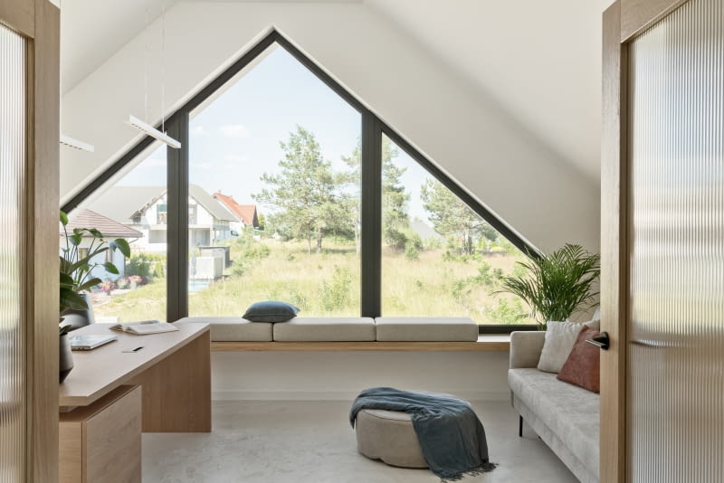 Do pokoju wstawiono szarobeżową sofę do spania marki Optisofa, przydatną, kiedy gabinet zmienia się w pokój gościnny.