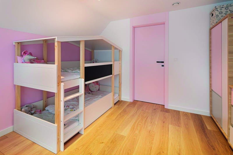 Pokój dziecięcy, czyli jedna z trzech sypialni znajdujących się na  piętrze. Oryginalnie, niesymetrycznie pomyślane dwupoziomowe łóżko, dzięki dwuspadowemu zadaszeniu przypominać może nieco  domek, również taki w wersji dla lalek... Kolorystykę całości dostosowano do upodobań małoletnich córek właścicieli