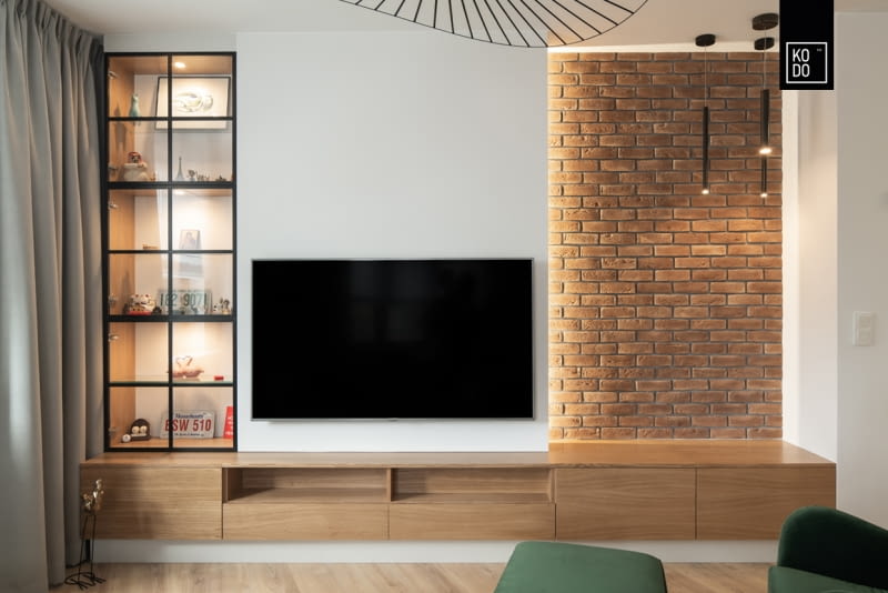 Powierzchnię poza ścianą, na której wisi telewizor, można wykorzystać do stworzenia nierozpraszającej uwagi aranżacji.