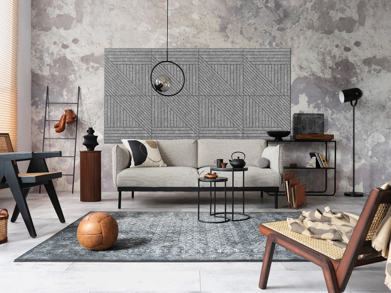 Ściana z efektem starego tynku wypadnie niebanalnie w otoczeniu nowoczesnego wyposażenia. Umieszczone na środku muru szare panele akustyczne dodatkowo wyeksponują oryginalność pomysłu i rangę stojącej tu sofy.