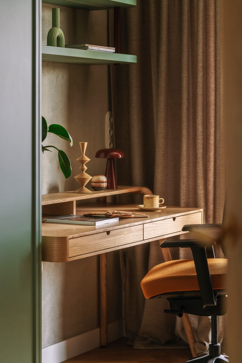 Pod ścianą, naprzeciwko sofy, stanęło drewniane biurko z szufladami i praktyczną nadstawką, zakupione w sklepie Westwing. Tło dla tego kącika pracy tworzy beżowy tynk strukturalny – identyczny jak w salonie, na ścianie z telewizorem.
