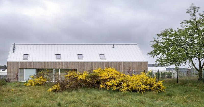 Projekt architektoniczny bryły tego budynku może rodzić różne skojarzenia, ale nie da się ukryć, że tropy wiodące do wyjściowego pomysłu na dom stodołę pozostały jednak bardzo wyraźne