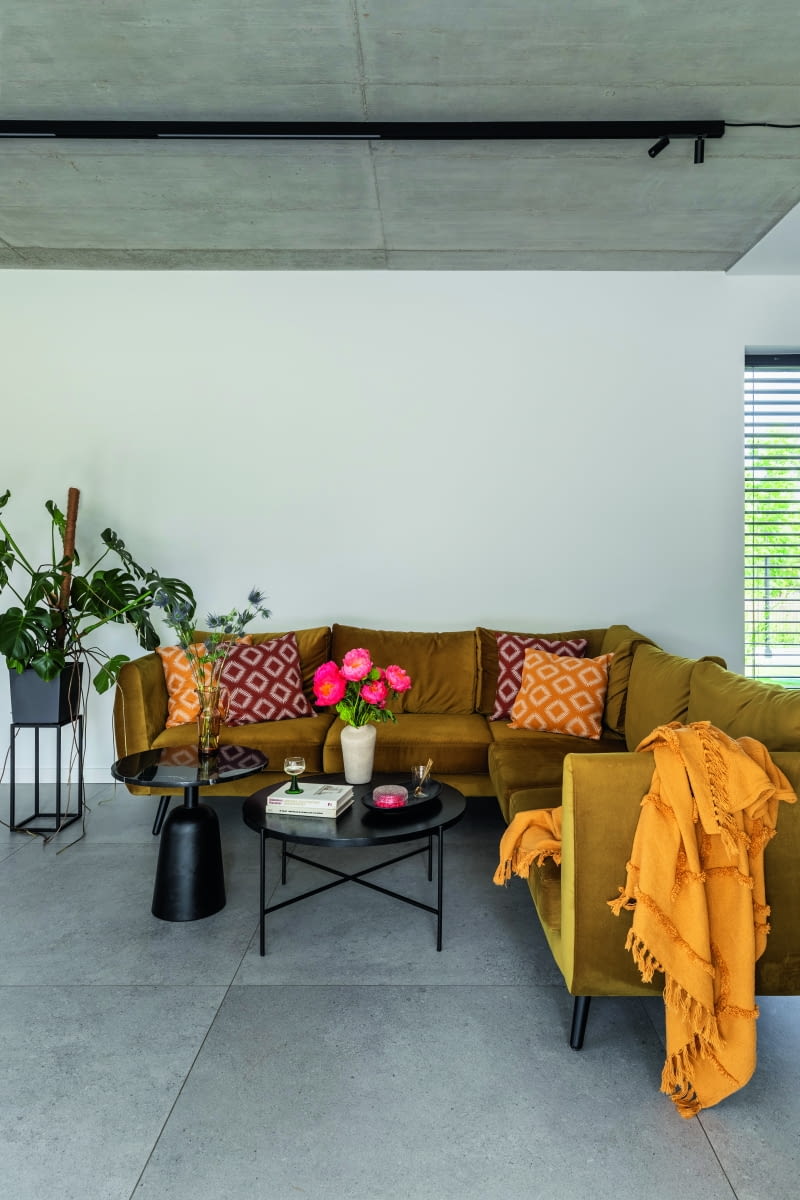 Miękkie obicia mebli, przyjemne w dotyku tkaniny, ciepła kolorystyka  i urozmaicone wzory dodatków przyczyniają się do tego, że z salonu,  oraz całego parteru, chce się korzystać – i to mimo industrialnych  szarości, które mamy tu zarówno pod stopami, jak i nad głową