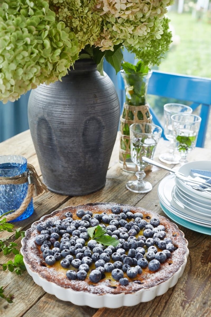 Letnią scenerię idealnie buduje dodatek niebieskiej barwy, przemyconej w kolorze krzeseł, ozdobnych poduszkach, lampionach, czy... w wypiekach i stroju pani domu.