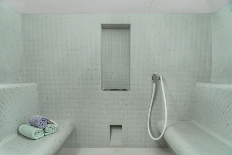 Strefa wellness na parterze: zastosowanie naturalnych materiałów, takich jak teksturowany wapień i drewno, nadaje pokojom spa uspokajającą atmosferę.