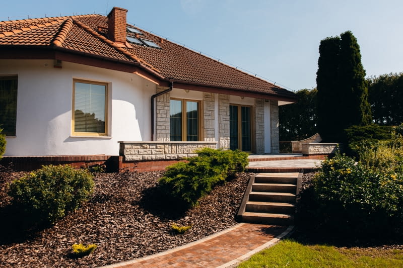 Przy domu w stylu klasycznym najlepiej sprawdzą się tradycyjne układy i stonowane barwy (beż, szary, brąz) Nawierzchnie