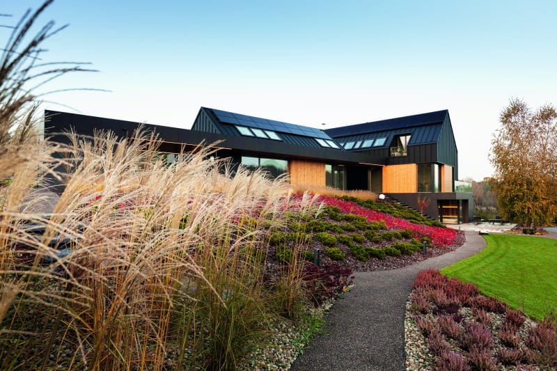 Trzy połączone ze sobą bryły, wyraźnie nawiązujące do tradycji budownictwa jednorodzinnego, ale jednocześnie mocno osadzone w nowoczesnym kontekście architektonicznym, otoczone starannie zaplanowanym ogrodem, umiejętnie wpisują się w malownicze wzgórz