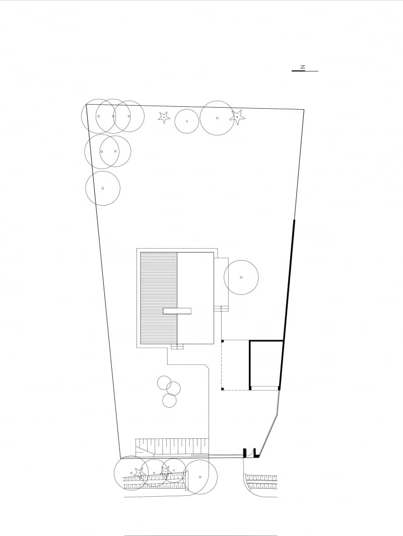 Rzut planu części należącej do małopolskich projektantów dobrze pokazuje, że musieli wpisać się w działkę o całkiem nieregularnym kształcie. Punkt ciężkości tworzy oczywiście budynek mieszkalny z przyległym doń pawilonem garażu. Zgodnie z okolicznym zwyczajem dom zwrócono ścianą szczytową w stronę ulicy dojazdowej. Dominantą przestrzenną ogrodu jest trawnik plus zachowany drzewostan