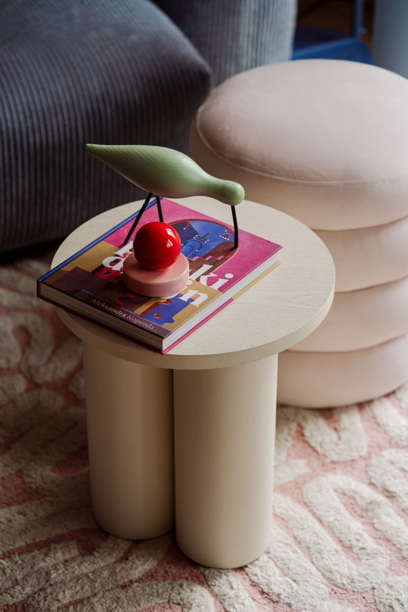 Pośród skarbów dekorujących mieszkanie na białym stoliku swoje miejsce znalazł przycisk do papieru Malwiny Konopackiej i ptasia figurka z Norman Copenhagen. Salonowy dywan jest z Jotexu.