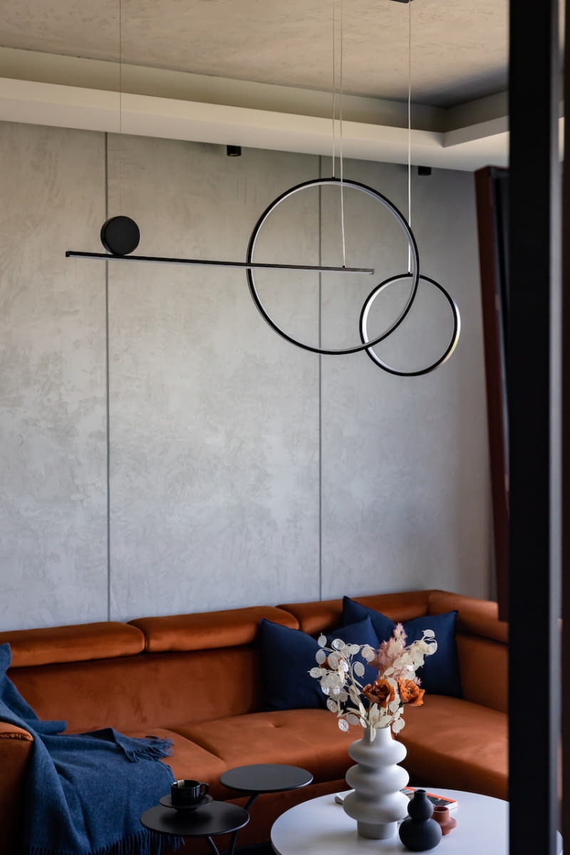 Nad kącikiem wypoczynkowym zawisła geometryczna lampa New Age marki Step into Design. Kompozycja LED-owych kół i listwy, z których jest zbudowana, dopełnia nowoczesny wystrój mieszkania.