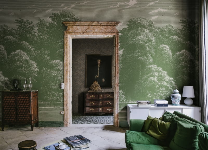 Eklektyczny salon z akcentami nowoczesności i klasyki zyskuje spokojny wystrój dzięki głębokiej zieleni tapicerki sofy i przedstawiającej bujny las tapecie marki REBEL WALLS.