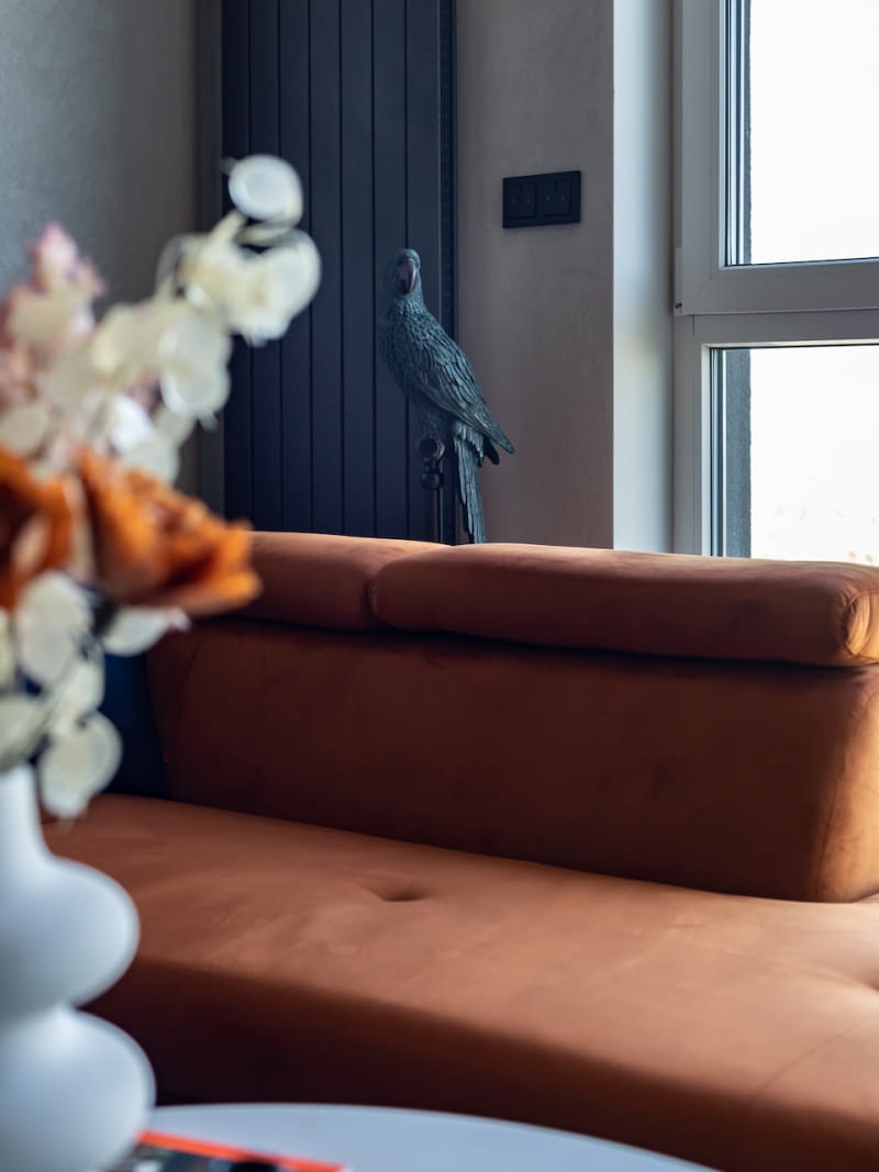 Ruda, welurowa narożna sofa ze sklepu Agata ociepla szarości i czernie salonowej aranżacji. Z nieskrywaną śmiałością kontrastuje z monochromatycznymi kolorami wnętrza. Sprawia, że serce bije mocniej.