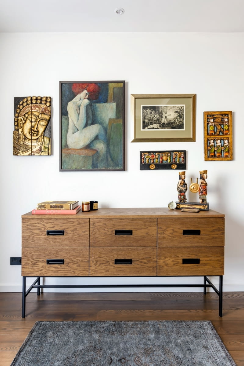 Ustawiona naprzeciwko łóżka komoda i ściana nad nią to idealne miejsce do ekspozycji sztuki i wakacyjnych pamiątek. Swoje miejsce znalazła tu grafika „Lunatyk” z aktem kobiecym oraz płaskorzeźby i wizerunek Buddy przywiezione z Indonezji.