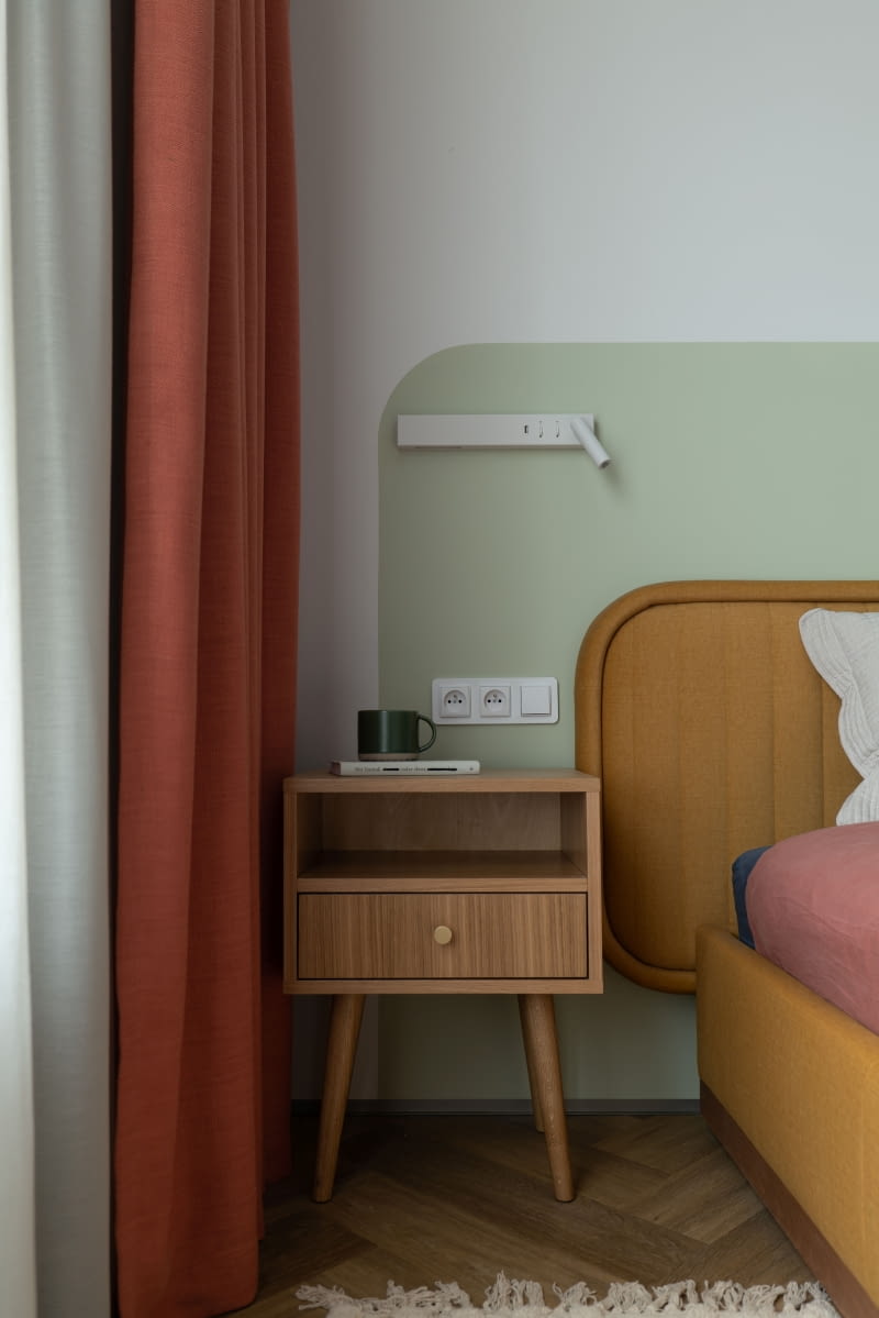 Białe kinkiety przy łóżku są z oferty marki Nova Luce, a szafki nocne od Scandicsofa. Jasna zieleń za zagłówkiem łóżka to ten sam kolor, którym wykończoną ścianę w kuchni.