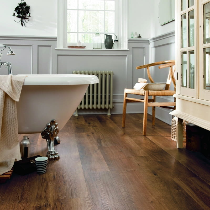 Wanna wolno stojąca na zdobionych nóżkach – nieodzowny element łazienki w stylu retro – tu pięknie skomponowana z podłogą winylową Designflooring Van Gogh VGW86T Classic Oak.