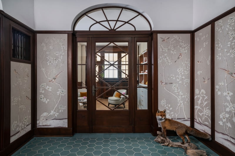 Willa w stylu secesyjnym niedaleko Zurychu: w okazałym holu wejściowym czekają na gości wspaniałe schody i ręcznie malowana lniana tapeta z motywem kwiatowym i ptakami.