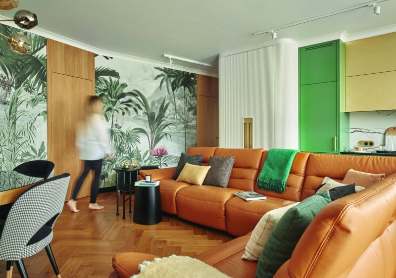 Przytulną aranżację przełamują zimne barwy – zgaszona zieleń obecna na frontach szafek kuchennych oraz tapecie, a także czerń zaakcentowana w kilku miejscach.