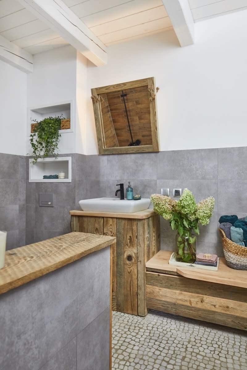 W oryginalnych meblach jest sporo miejsca do przechowywania – pod umywalką kryją się półki na kosmetyki, a pod podnoszoną klapą skrzyni można schować ręczniki. W tej łazience funkcjonalność nie ustępuje naturalnemu urokowi wnętrza.