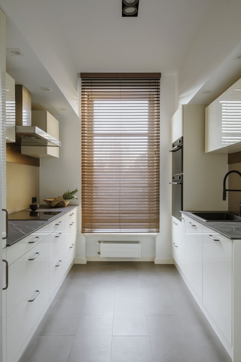 Choć kuchnia jest odrębnym względem części dziennej pomieszczeniem, jej wystrój harmonijnie dostosowano do reszty mieszkania. Panuje tu ponadczasowa prostota we współczesnym wydaniu,  z wykorzystaniem barw ziemi.